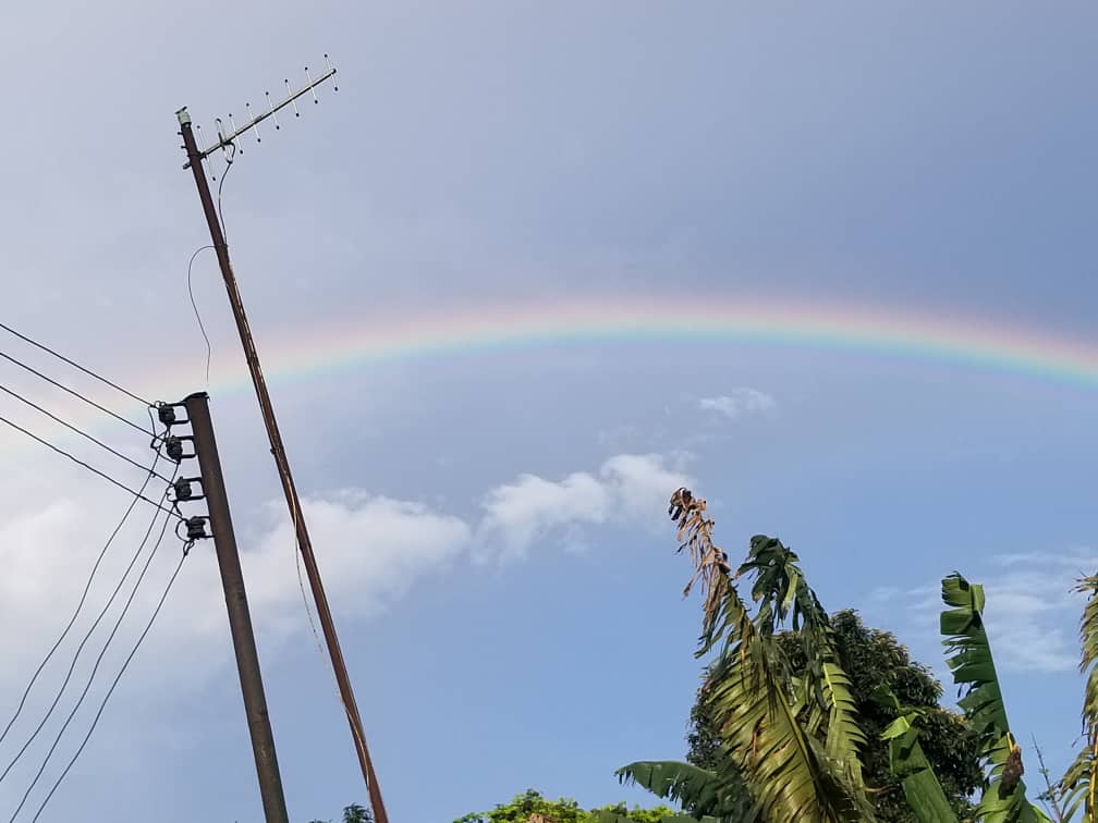 Rainbow across the blue sky with clouds