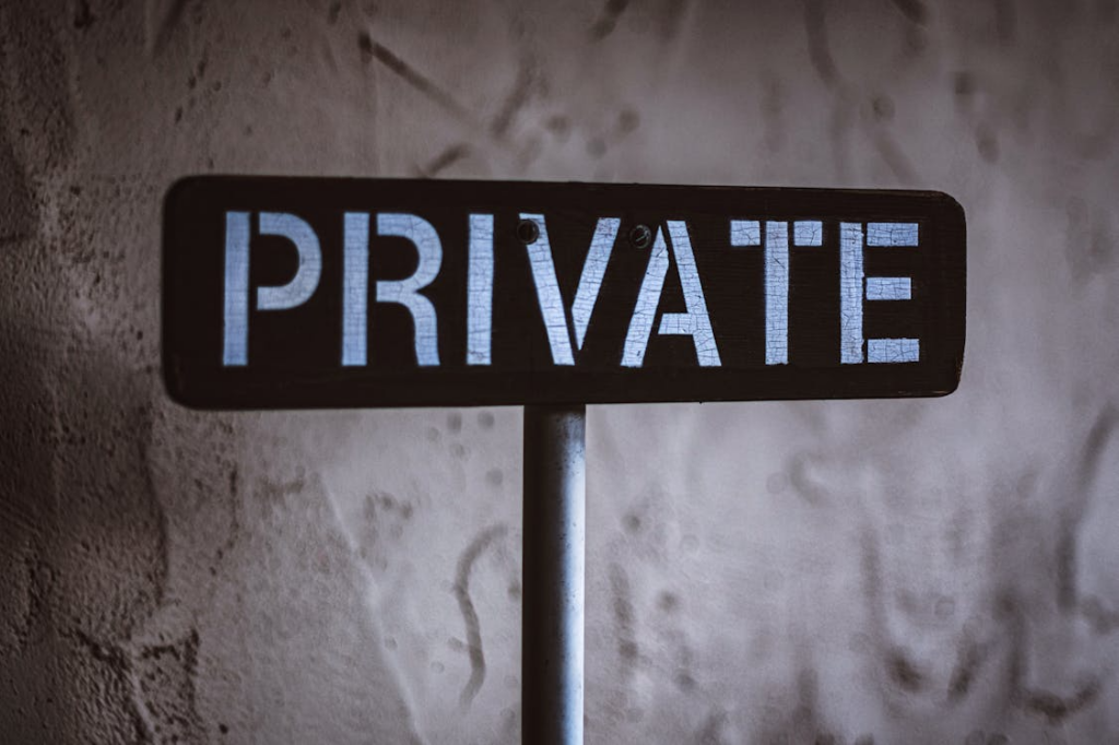 Black and white wooden sign saying “Private” behind white concrete. 