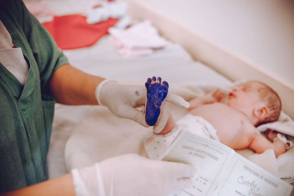 Hands processing a birth certificate with baby footprints and fingerprints visible on the papers.