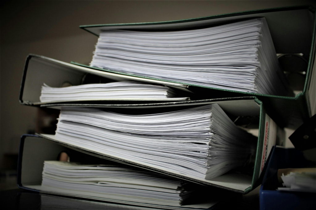 Stack of three office binders filled with documents representing administrative record-keeping systems.