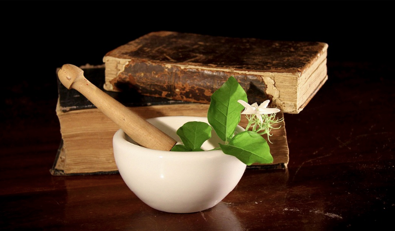 Image of a mini mortar and pestle, with herbs and books
