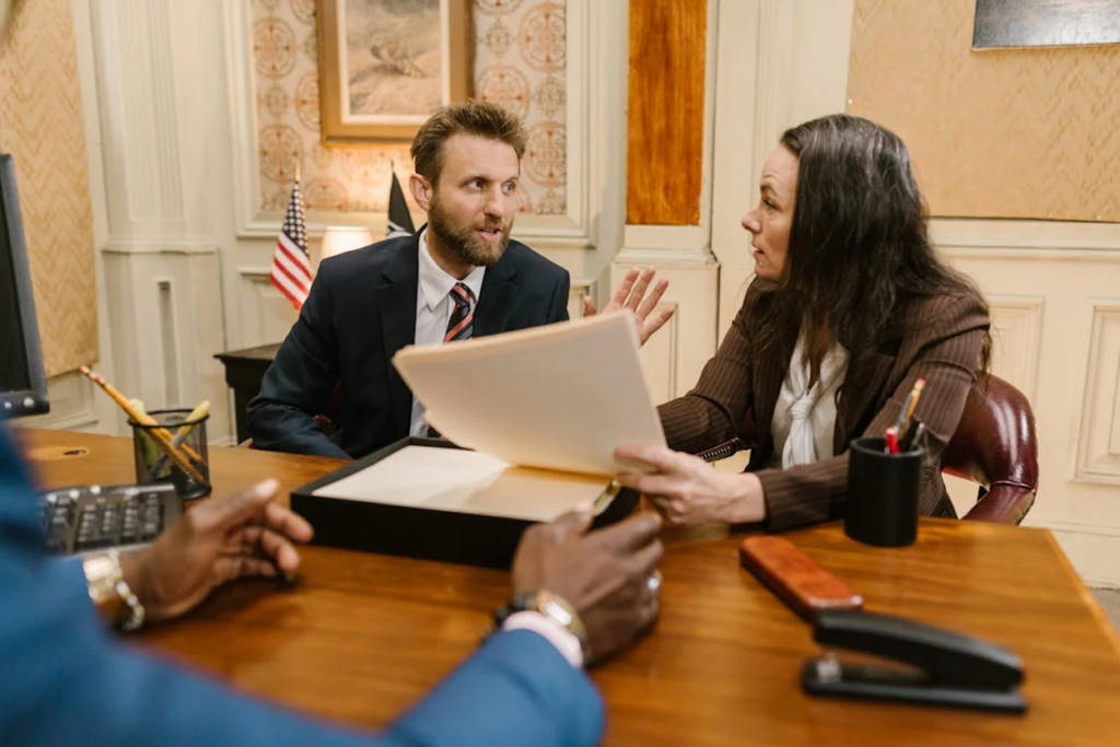 Three professionals in business attire having an intense discussion over documents at an office desk