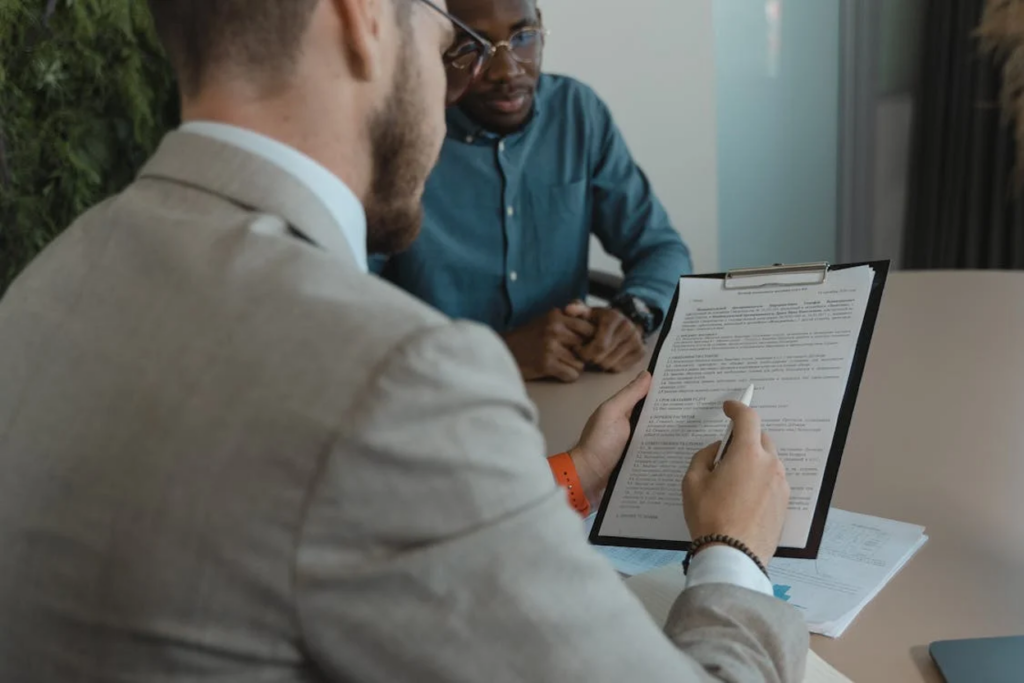 Two men in a business meeting reviewing a document on a clipboard