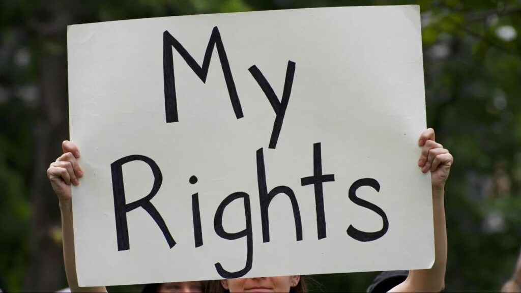 A person holding a handwritten sign that reads "My Rights".