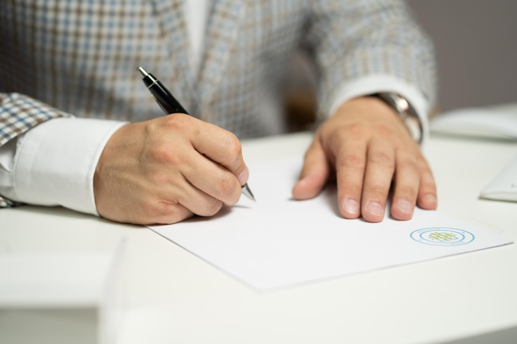 A man on gray suit signing a certificate