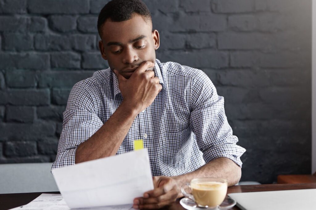Person sitting at a desk, carefully reviewing IRS tax filing documents and income reports.

