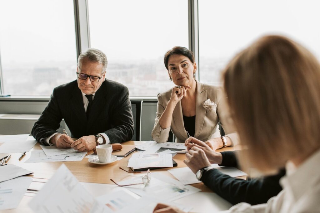 Professionals reviewing documents and charts during a business meeting at a conference table.