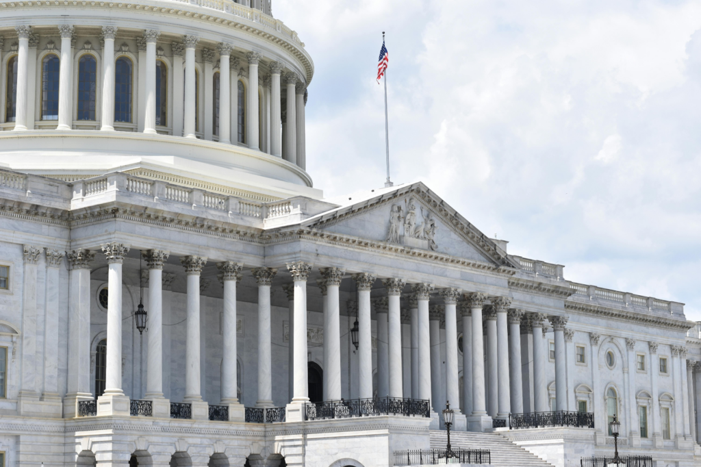 Close-up of the U.S. Capitol building's columned facade with dome and American flag.