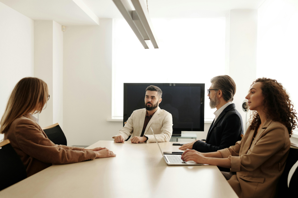 Four professionals seated around a conference table in a modern meeting room.