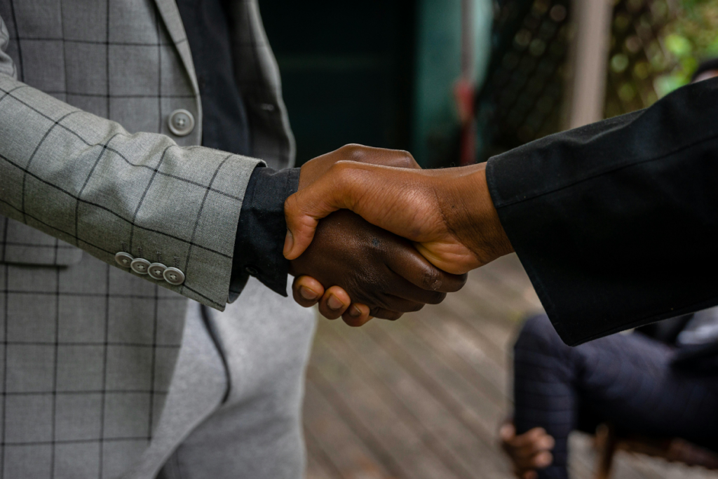Close-up of two people in formal suits shaking hands in a professional setting