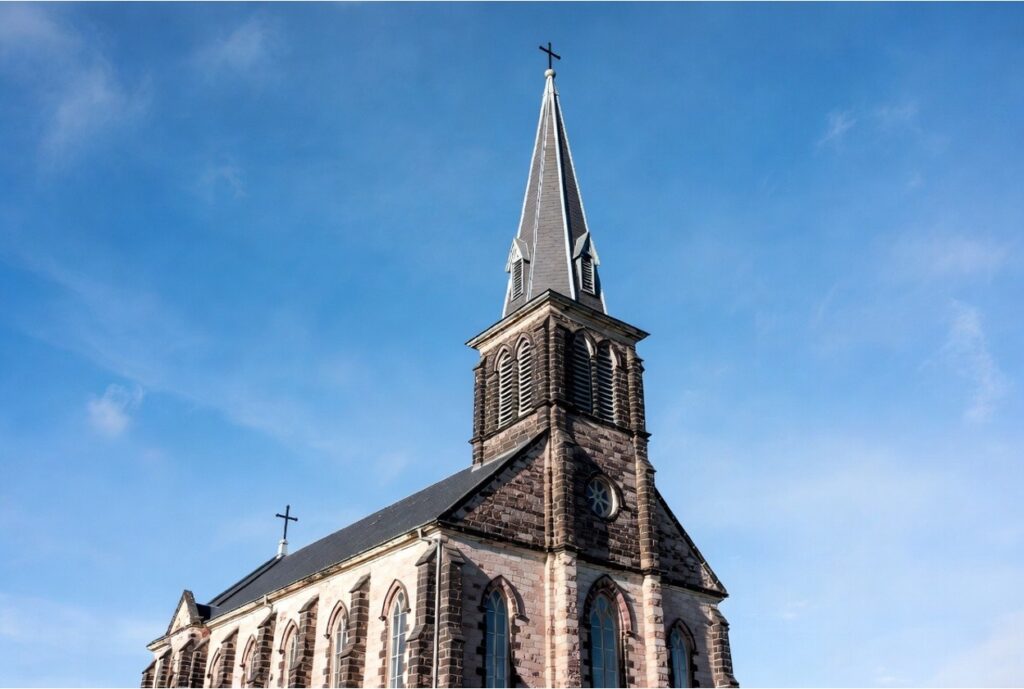Historic church building with a cross-topped steeple against a blue sky