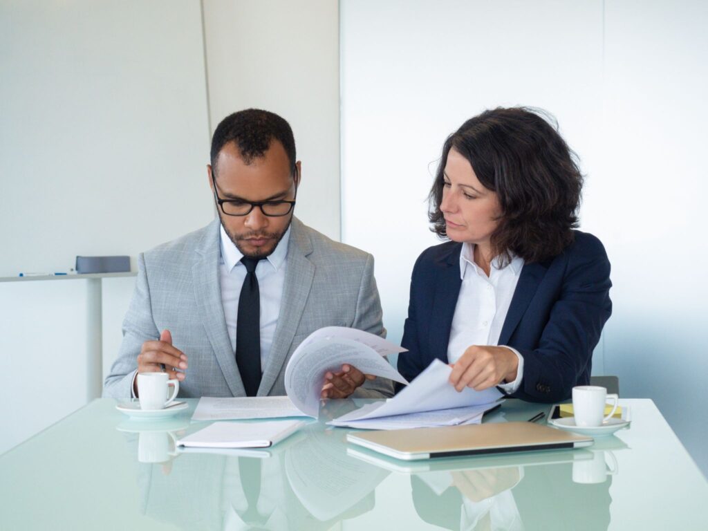 A legal consultant and client sitting at a desk reviewing and drafting a private membership association document.