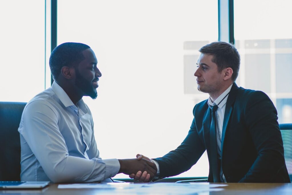 A church administrator shaking hands with a foundation representative in an office.