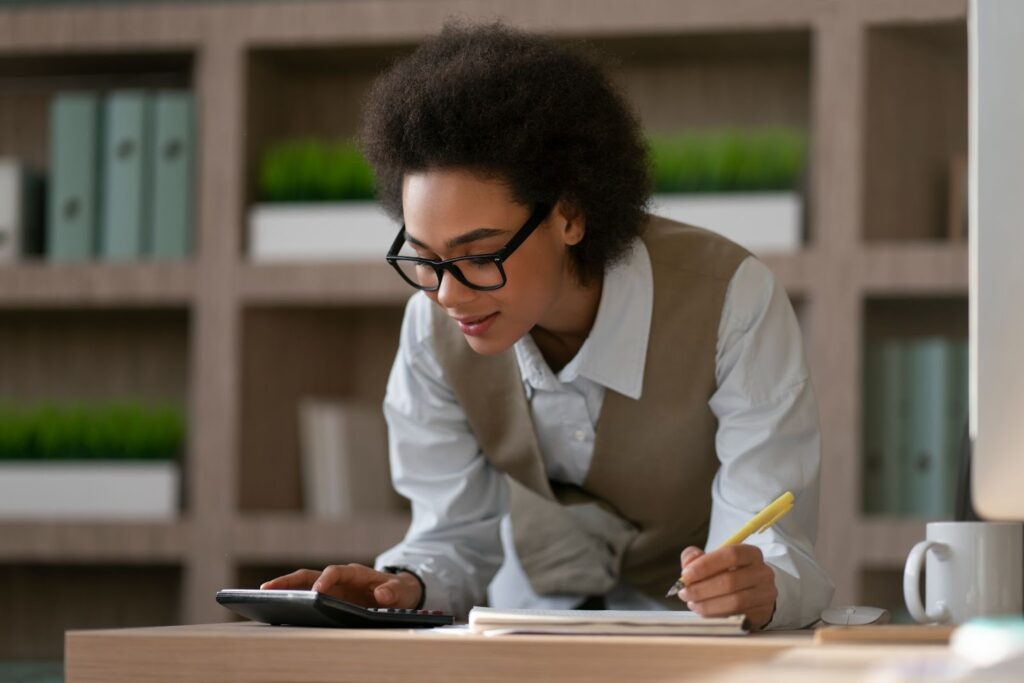 A taxpayer calculating charitable contribution deductions on tax forms with a calculator.
