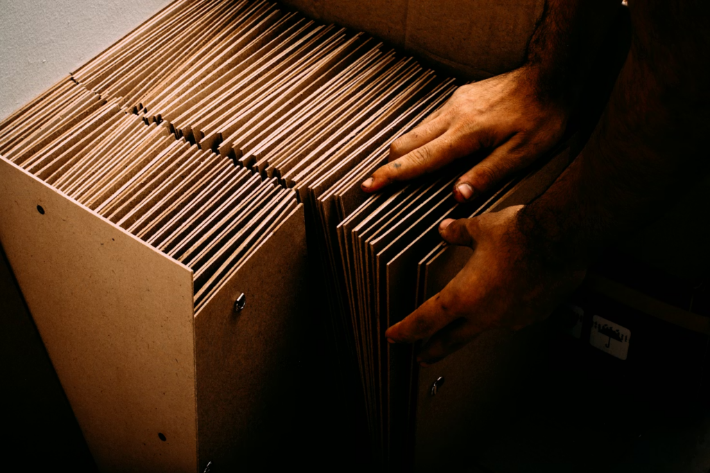 Man reaching into a cardboard box filled with organized file folders.