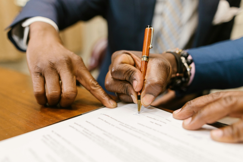 Close-up of a person signing a formal document with a pen on a desk.
