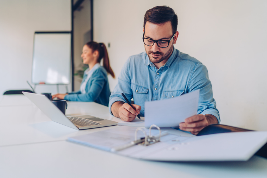 Nonprofit administrator reviewing 501(c)(3) and 501(c)(2) filing paperwork at a desk