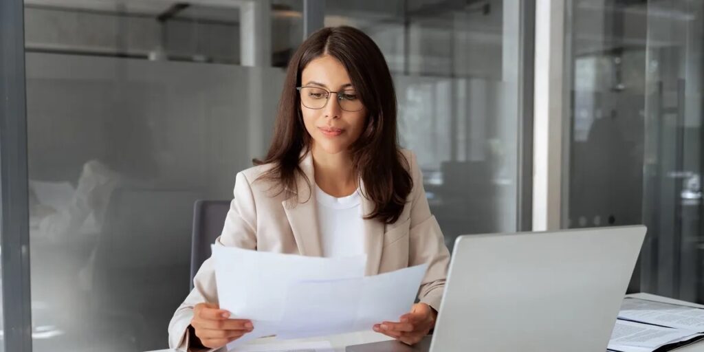 Nonprofit administrator reviewing IRS compliance paperwork at her desk to verify her organization's 501(c)(3) statu