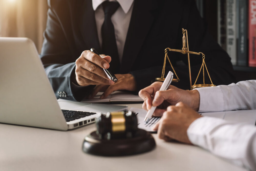 Attorney reviewing PMA formation documents with a client, gavel and scales of justice visible on the desk.