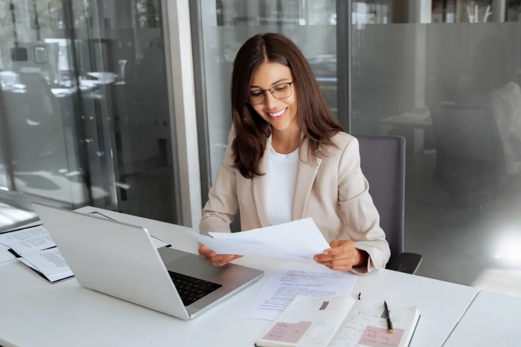 Professional reviewing PMA membership agreement paperwork with laptop and annotated notebook for tracking document amendments.