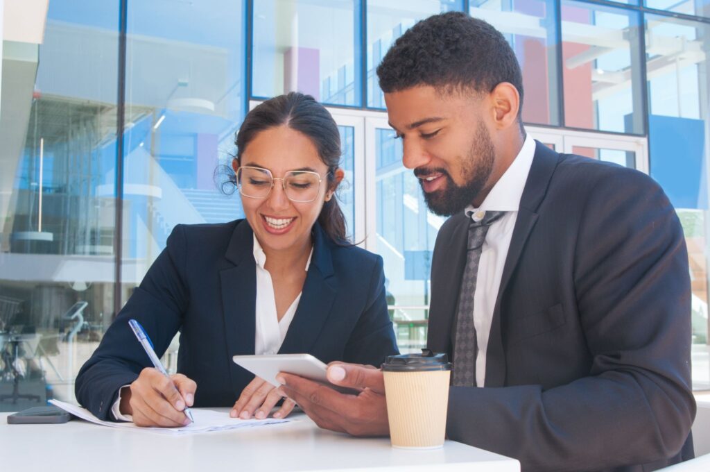 Small business owner signing LLC formation documents with a legal advisor present.