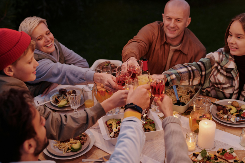 A group of family and friends clinking glasses over a candlelit dinner table filled with food.