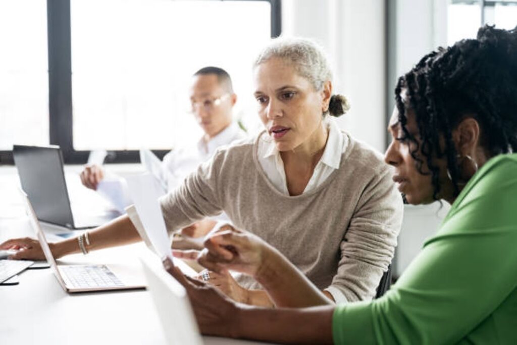 Senior financial advisor reviewing trust tax documents with a client at a conference room table.
