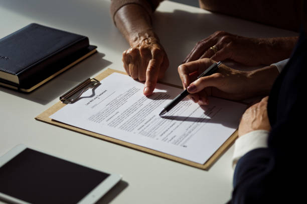 Two people reviewing and discussing a legal document on a clipboard beside a notebook and tablet.