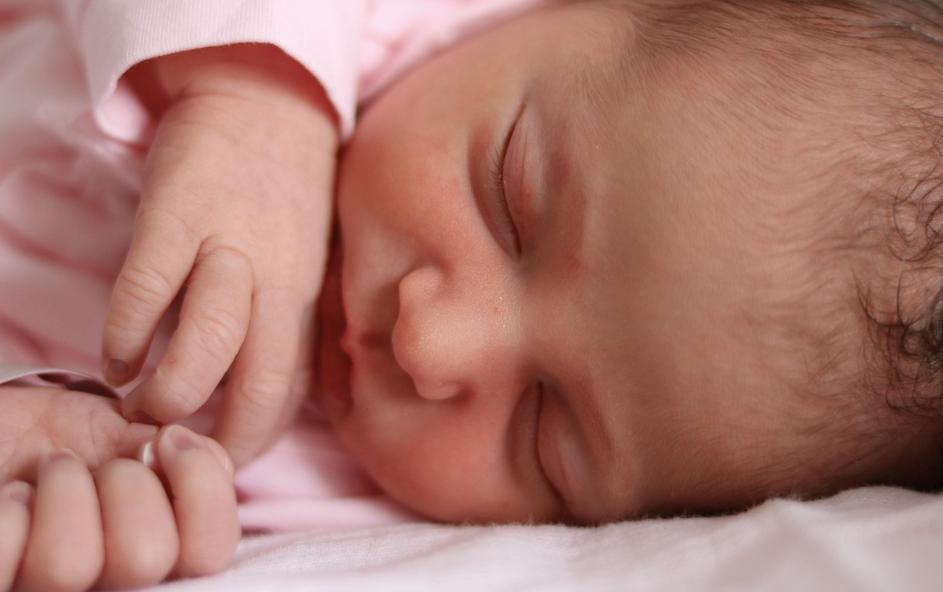 A newborn baby lying peacefully in a hospital bed.Â