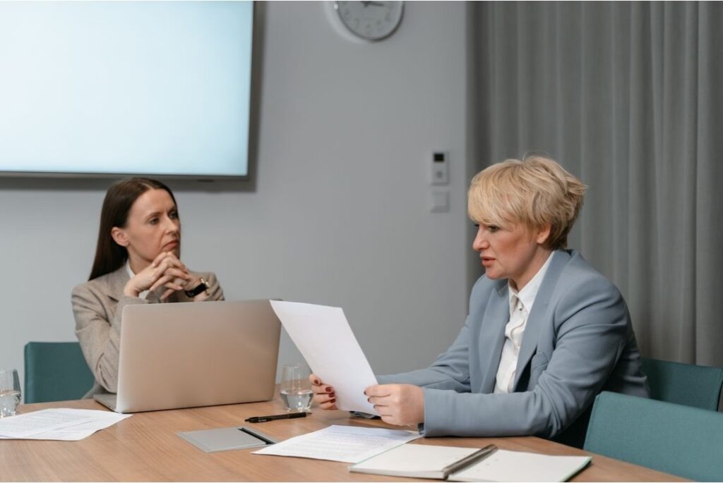 Two professionals reviewing trust planning documents during a meeting in a conference room. 