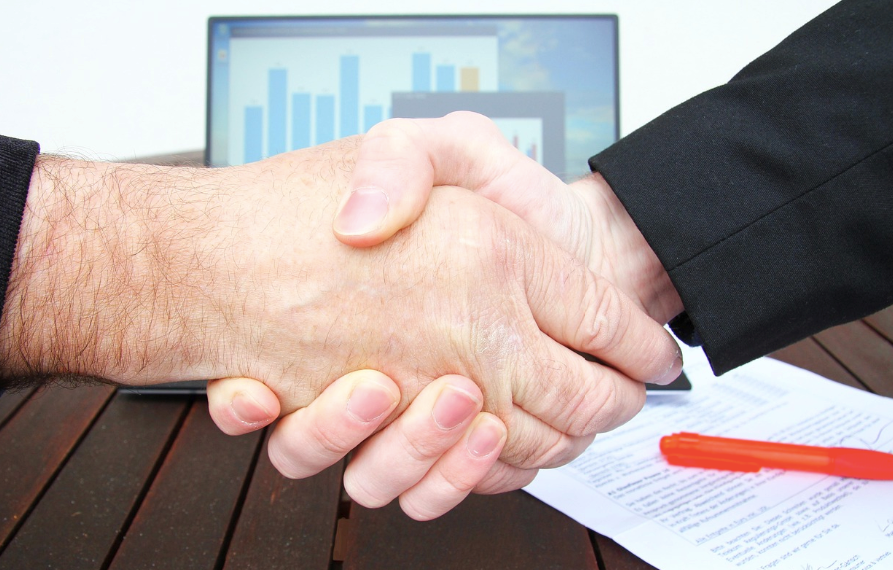 An employer and employee shaking hands after signing an agreement.