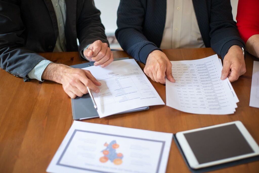 Professionals review nonprofit tax compliance documents and financial reports at a table.